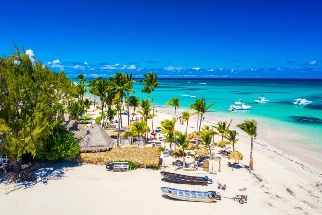 Beautiful atlantic tropical beach with palms, straw umbrellas and boats. Bavaro, Punta Cana, Dominican Republic